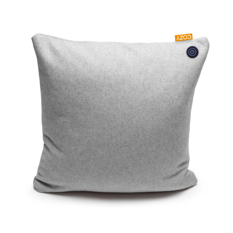 The COZY Heated Cushion Cordless - UNA (45cm x 45cm) by Cozy Cushion EU is a light gray square pillow with a small orange COZY tag and round black power button, offering soothing infrared warmth anywhere, cordless and convenient.