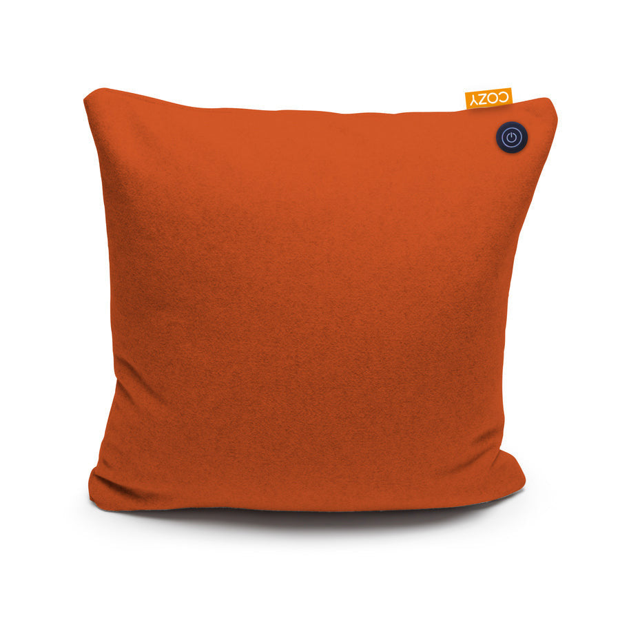 The COZY Heated Cushion Cordless - UNA (45cm x 45cm) by Cozy Cushion EU is a square burnt orange pillow featuring a small yellow COZY tag and a circular black button. It uses cordless infrared technology to deliver gentle, soothing warmth.