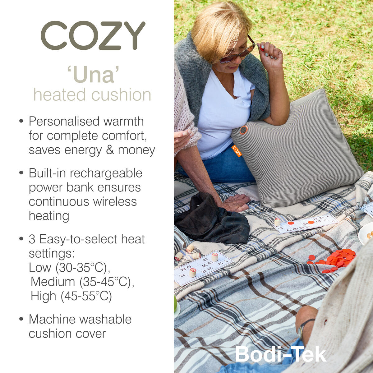 A woman sits outdoors on a patterned blanket, holding the COZY Heated Cushion Cordless - UNA Knitted (45cm x 45cm) by Cozy Cushion EU. Beside her is a heating controller, with text highlighting its features.