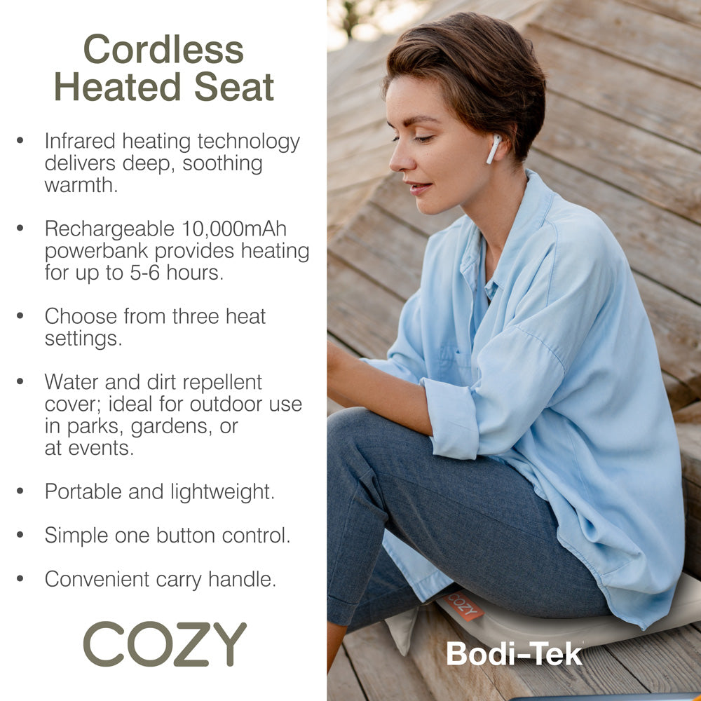 A woman relaxes outdoors on the COZY Cordless Heated Seat Pad - JORD by Cozy Cushion EU, featuring infrared warmth, a rechargeable battery, three heat settings, water- and dirt-repellent design, portability, easy controls, and a handy carry handle.