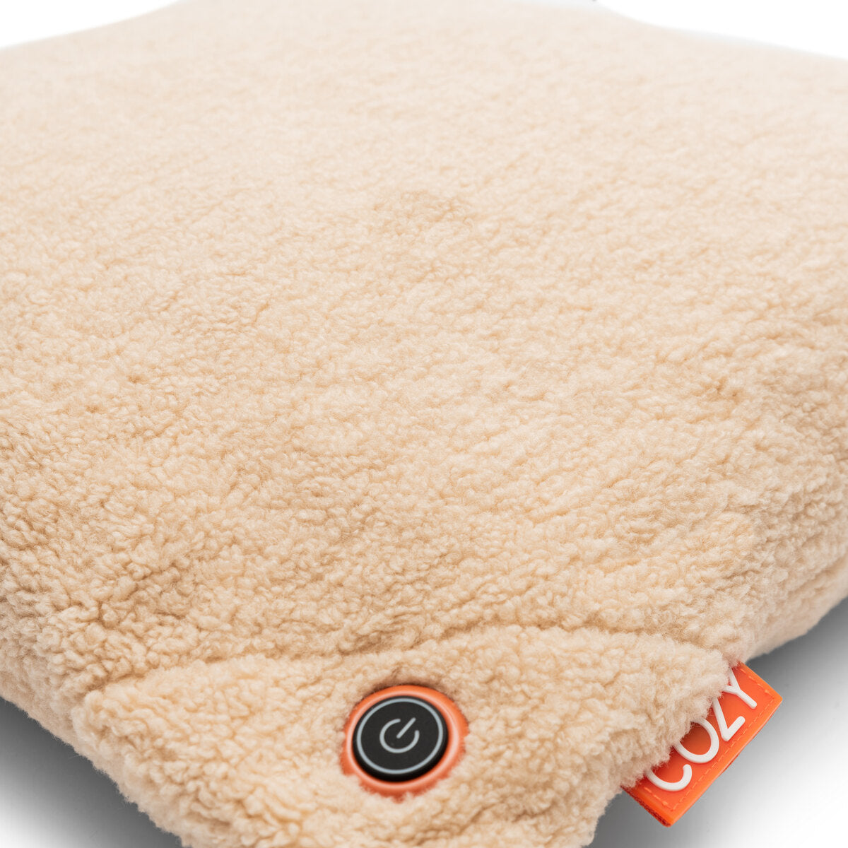 A close-up of the COZY Heated Cushion Cordless - UNA Woolly (45cm x 45cm) by Cozy Cushion EU shows its beige, fluffy design with a visible power button and an orange COZY tag on one corner.