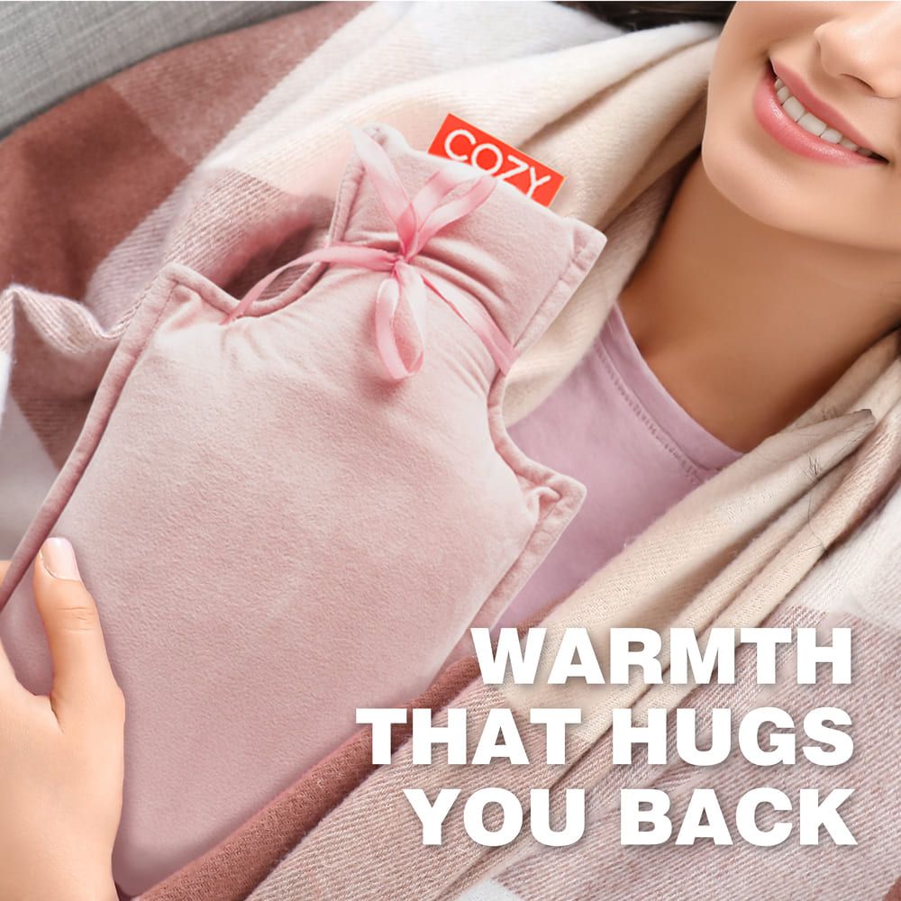 A person holds the UNA Rechargeable Hot Water Bottle by Cozy Cushion EU, wrapped in a cozy plaid blanket. The bold white text reads: WARMTH THAT HUGS YOU BACK.