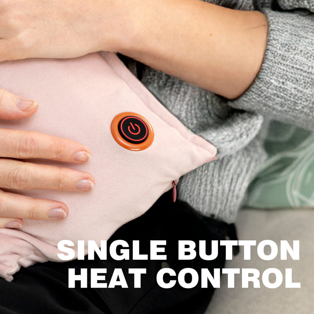 A person rests their hands on a pink UNA Rechargeable Hot Water Bottle from Cozy Cushion EU, featuring a single red power button. SINGLE BUTTON HEAT CONTROL is displayed at the bottom of the image.